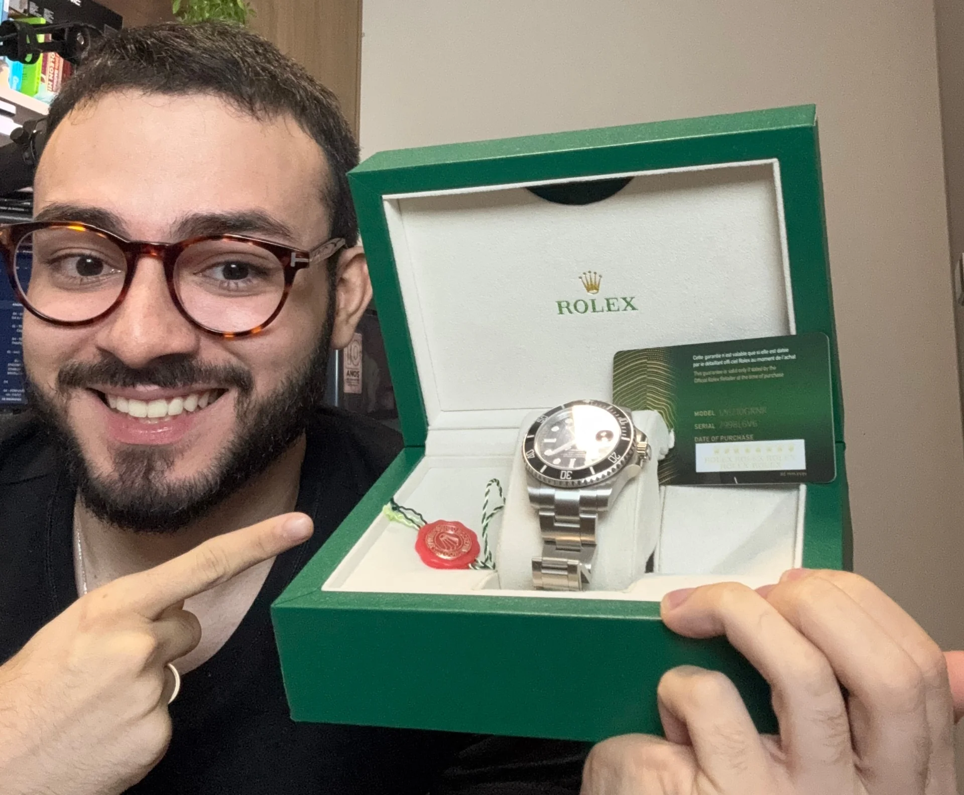 Homem apontando para um relógio Rolex dentro da caixa verde original